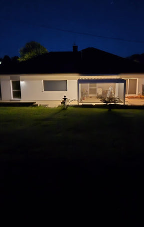 Einfamilienhaus bei Nacht mit beleuchteter Pergolux Pergola auf der Terrasse.