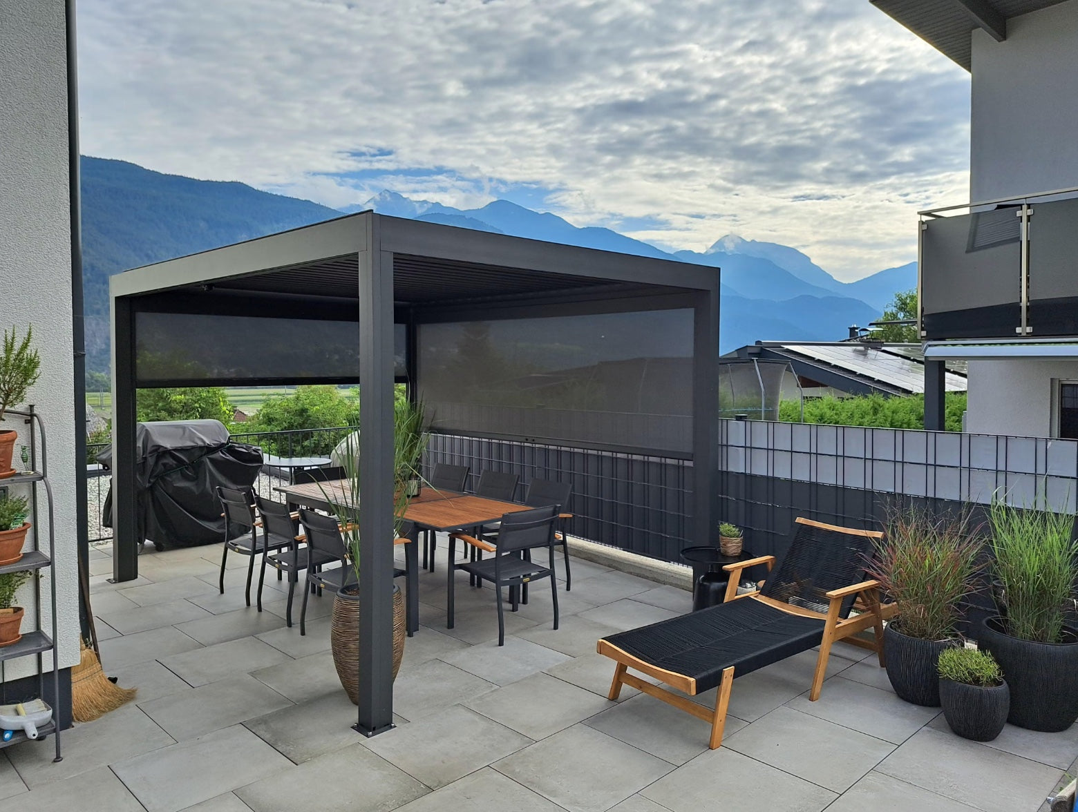 Pergolux Pergola auf einer modernen Terrasse mit seitlichen Screens, Essbereich und Blick auf die Berge.