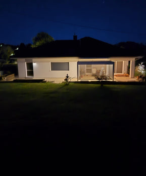 Einfamilienhaus bei Nacht mit beleuchteter Pergolux Pergola auf der Terrasse.
